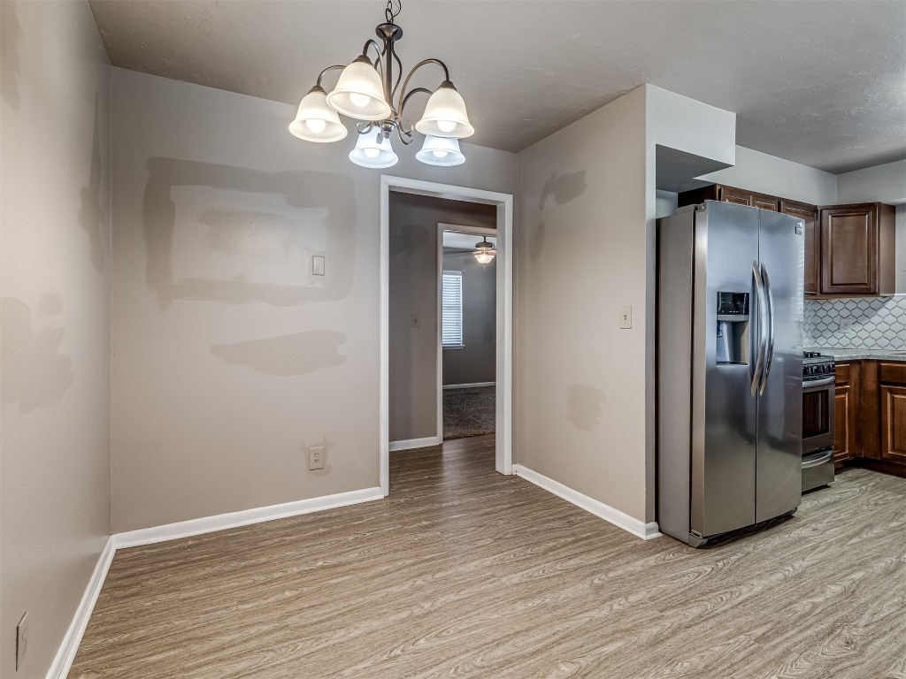 1706 Janeen Street, Yukon, OK 73099 kitchen featuring appliances with stainless steel finishes, light hardwood / wood-style flooring, backsplash, ceiling fan with notable chandelier, and pendant lighting