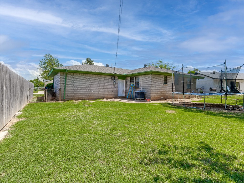 1706 Janeen Street, Yukon, OK 73099 back of property featuring a trampoline, a patio, central AC unit, and a lawn