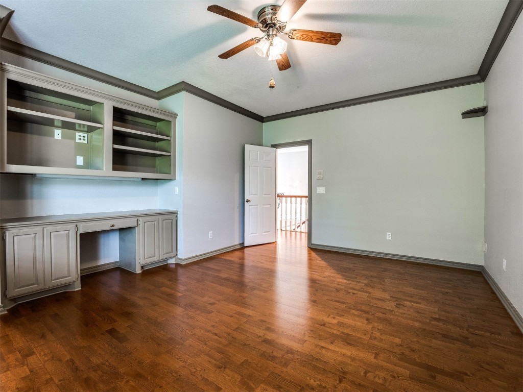 1307 Brookside Drive, Norman, OK 73072 unfurnished office featuring crown molding, built in desk, dark hardwood / wood-style flooring, and ceiling fan