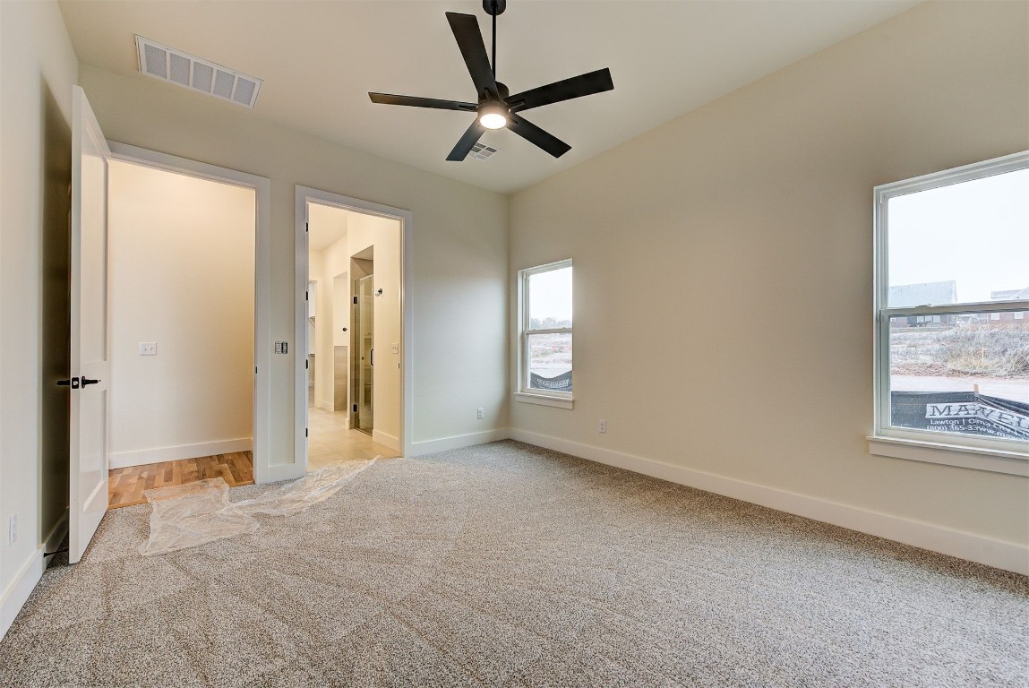 4124 Emery Drive, Edmond, OK 73034 unfurnished bedroom with carpet floors, ceiling fan, and multiple windows