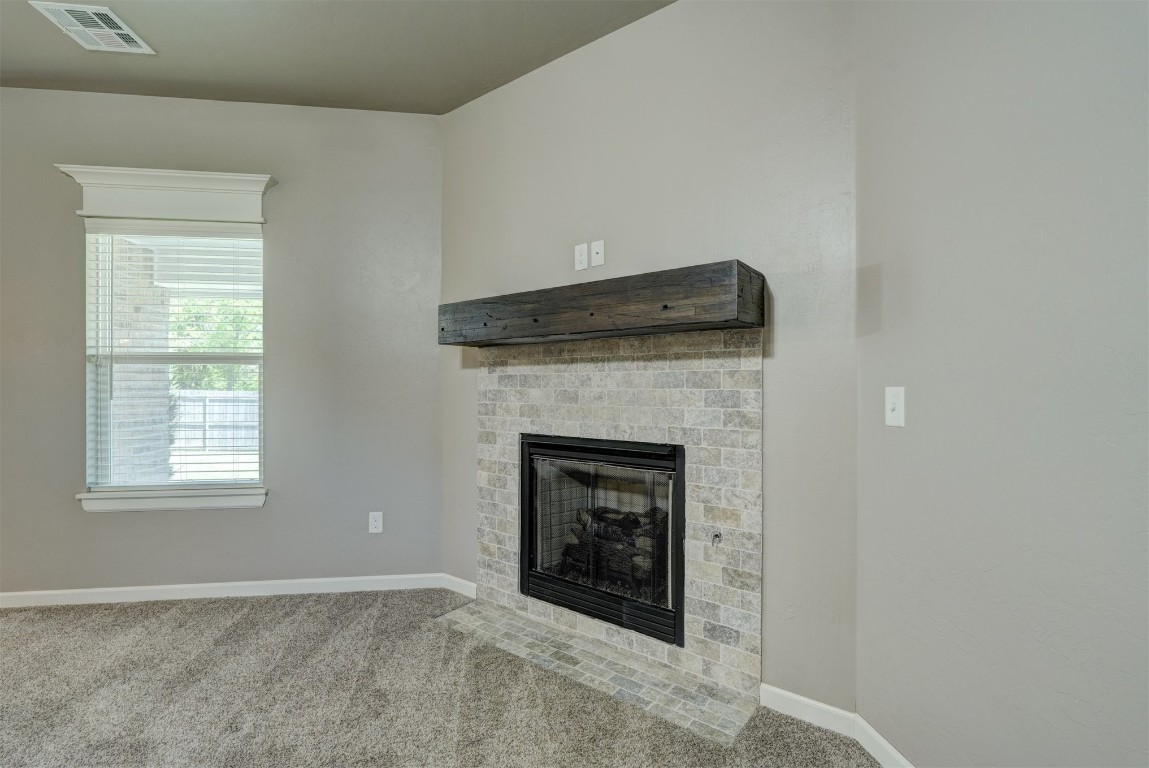 1727 W Blake Way, Mustang, OK 73064 unfurnished living room with carpet flooring and a fireplace