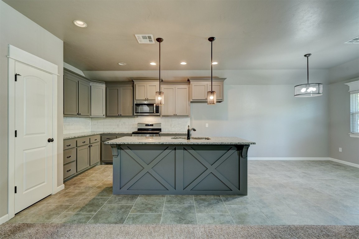 1727 W Blake Way, Mustang, OK 73064 kitchen featuring light tile floors, backsplash, decorative light fixtures, stainless steel appliances, and a center island with sink