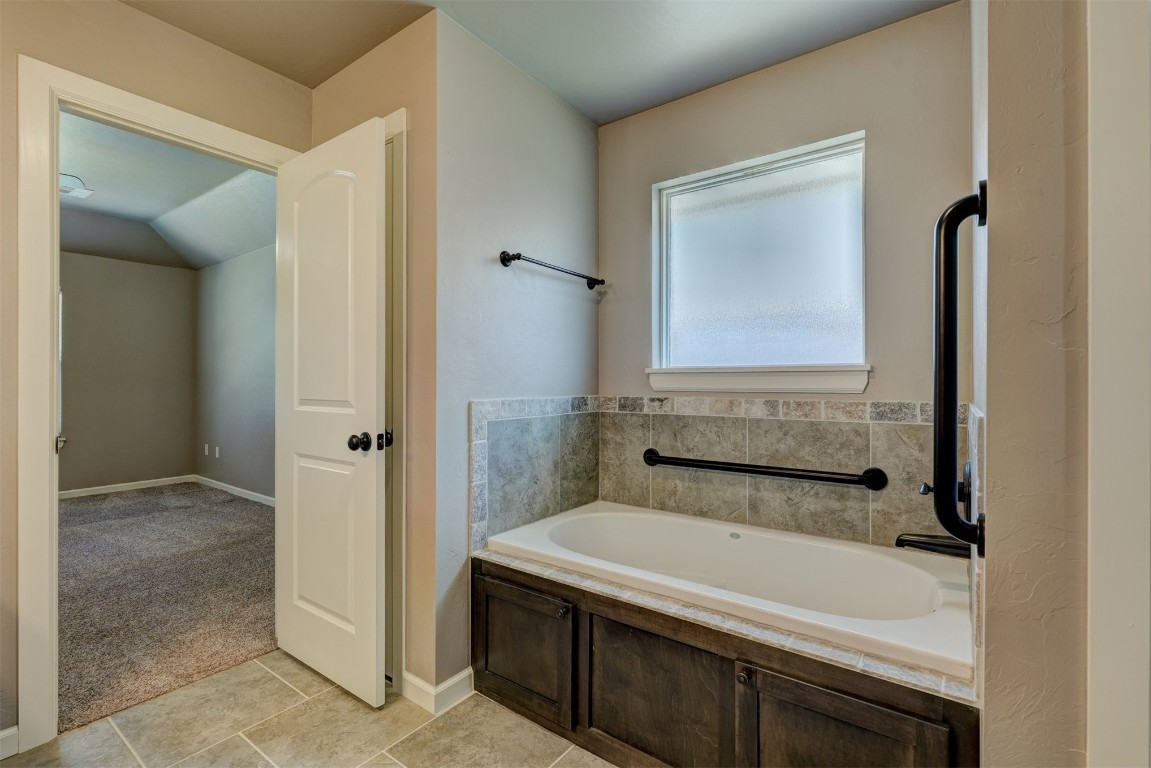 1727 W Blake Way, Mustang, OK 73064 bathroom with tile flooring, lofted ceiling, and a bathtub