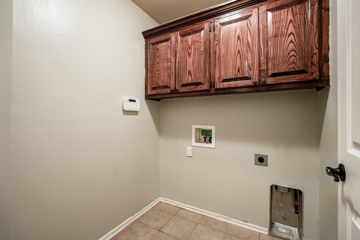 713 N Bobcat Way, Mustang, OK 73064 laundry room with electric dryer hookup, cabinets, light tile floors, and hookup for a washing machine