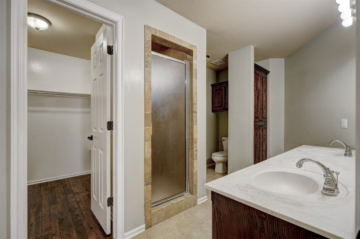 713 N Bobcat Way, Mustang, OK 73064 bathroom with walk in shower, double vanity, toilet, and hardwood / wood-style floors
