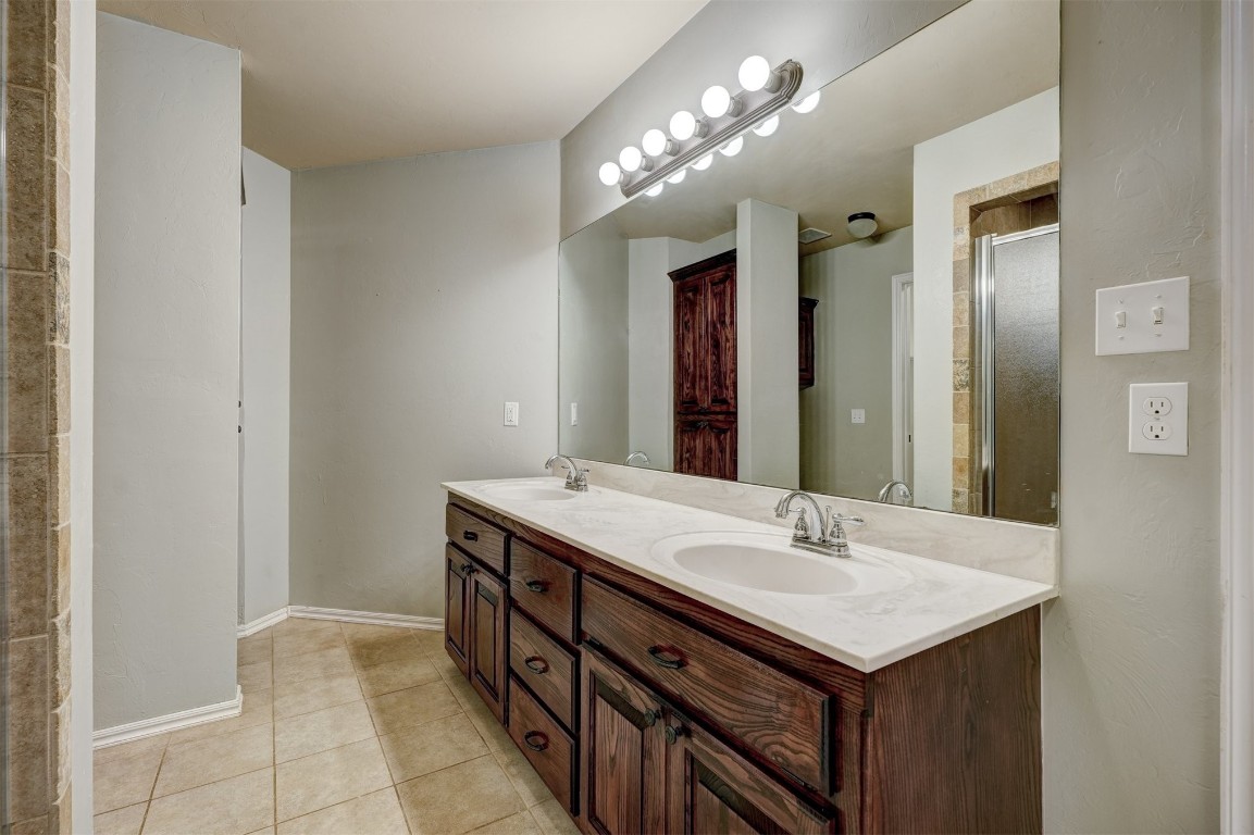 713 N Bobcat Way, Mustang, OK 73064 bathroom featuring a shower with shower door, tile flooring, and dual vanity
