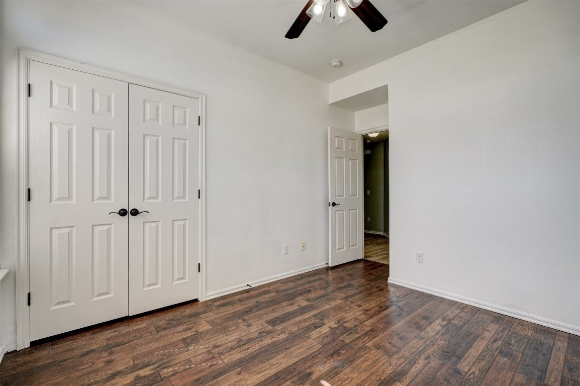 713 N Bobcat Way, Mustang, OK 73064 unfurnished bedroom featuring a closet, dark wood-type flooring, and ceiling fan