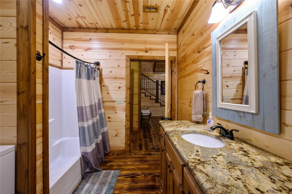 68 Stevens Road, Broken Bow, OK 74728 full bathroom with wood-type flooring, vanity, shower / tub combo, and wooden walls
