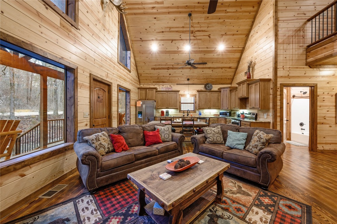 68 Stevens Road, Broken Bow, OK 74728 living room featuring wood walls, ceiling fan, high vaulted ceiling, and hardwood / wood-style floors