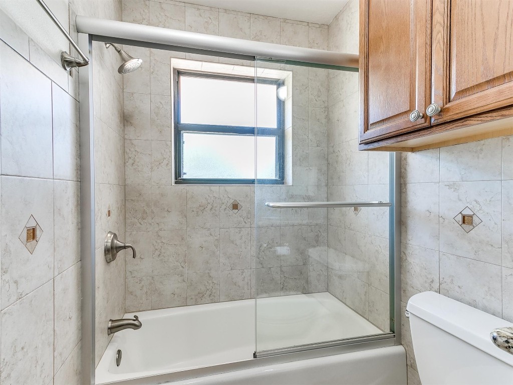3908 Corbett Drive, Del City, OK 73115 bathroom featuring tile walls, toilet, and shower / bath combination with glass door