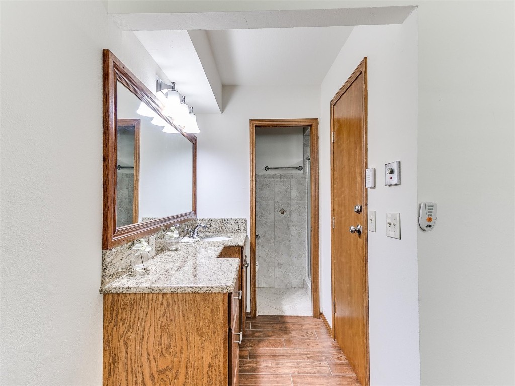 3908 Corbett Drive, Del City, OK 73115 bathroom with tiled shower, vanity, and hardwood / wood-style floors
