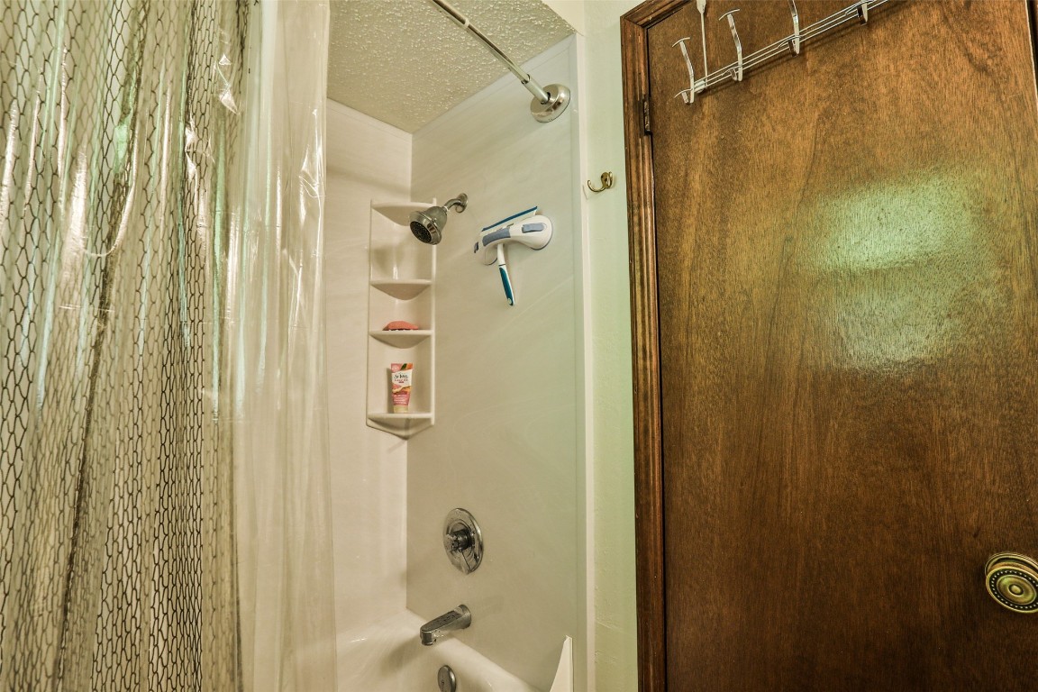 2012 N Santa Fe Avenue, Moore, OK 73160 interior details with shower / bath combo and a textured ceiling