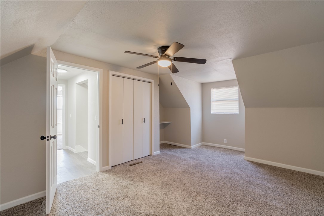 3820 Tranquill Terrace, Guthrie, OK 73044 additional living space with vaulted ceiling, ceiling fan, carpet flooring, and a textured ceiling