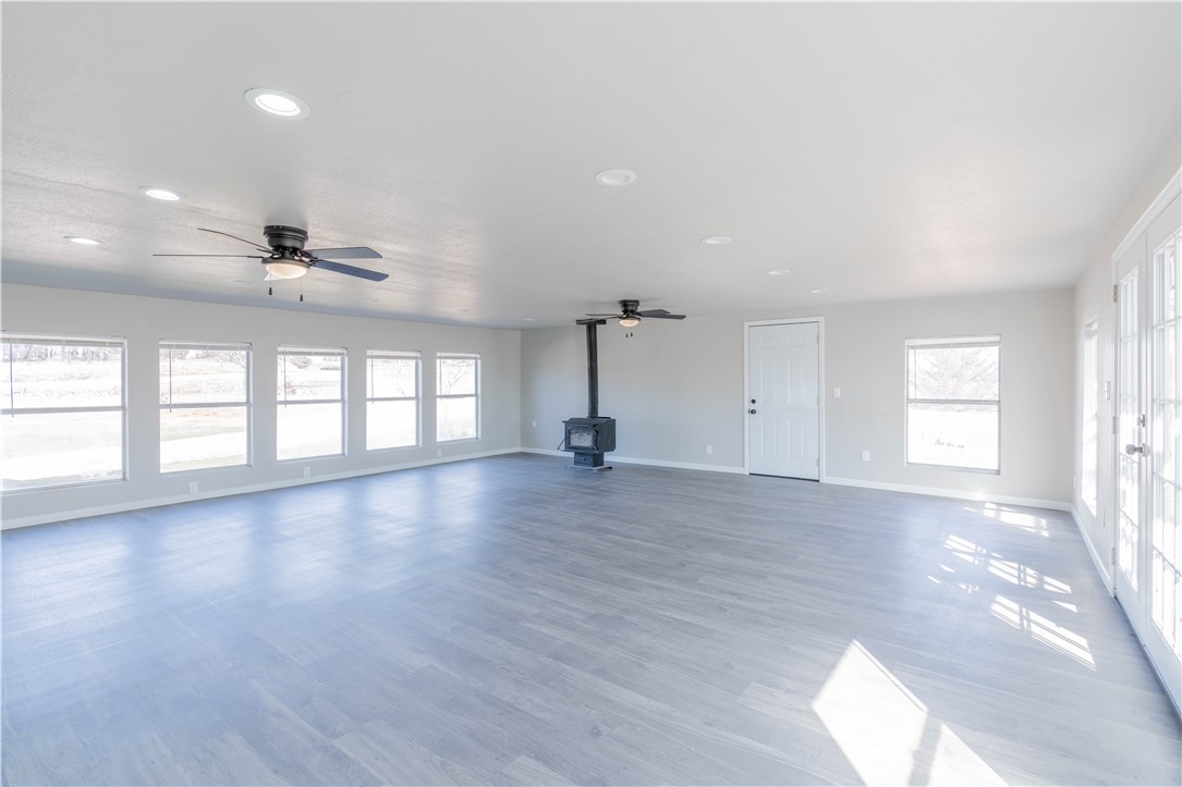 3820 Tranquill Terrace, Guthrie, OK 73044 empty room featuring plenty of natural light, a wood stove, ceiling fan, and hardwood / wood-style flooring