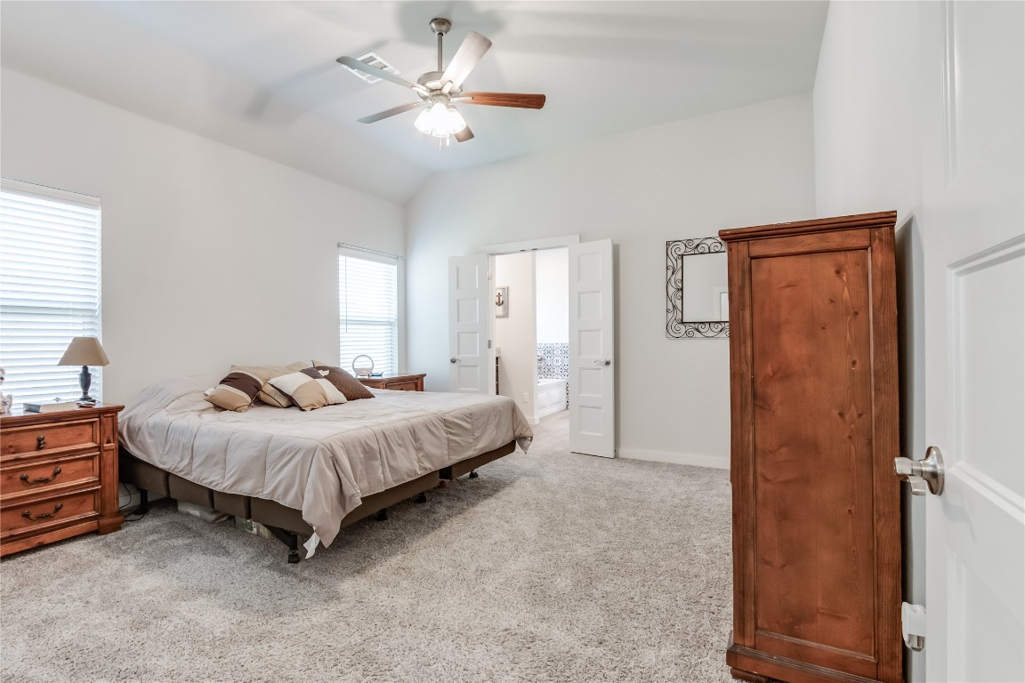 11636 NW 109th Street, Yukon, OK 73099 carpeted bedroom with ceiling fan, vaulted ceiling, and ensuite bathroom
