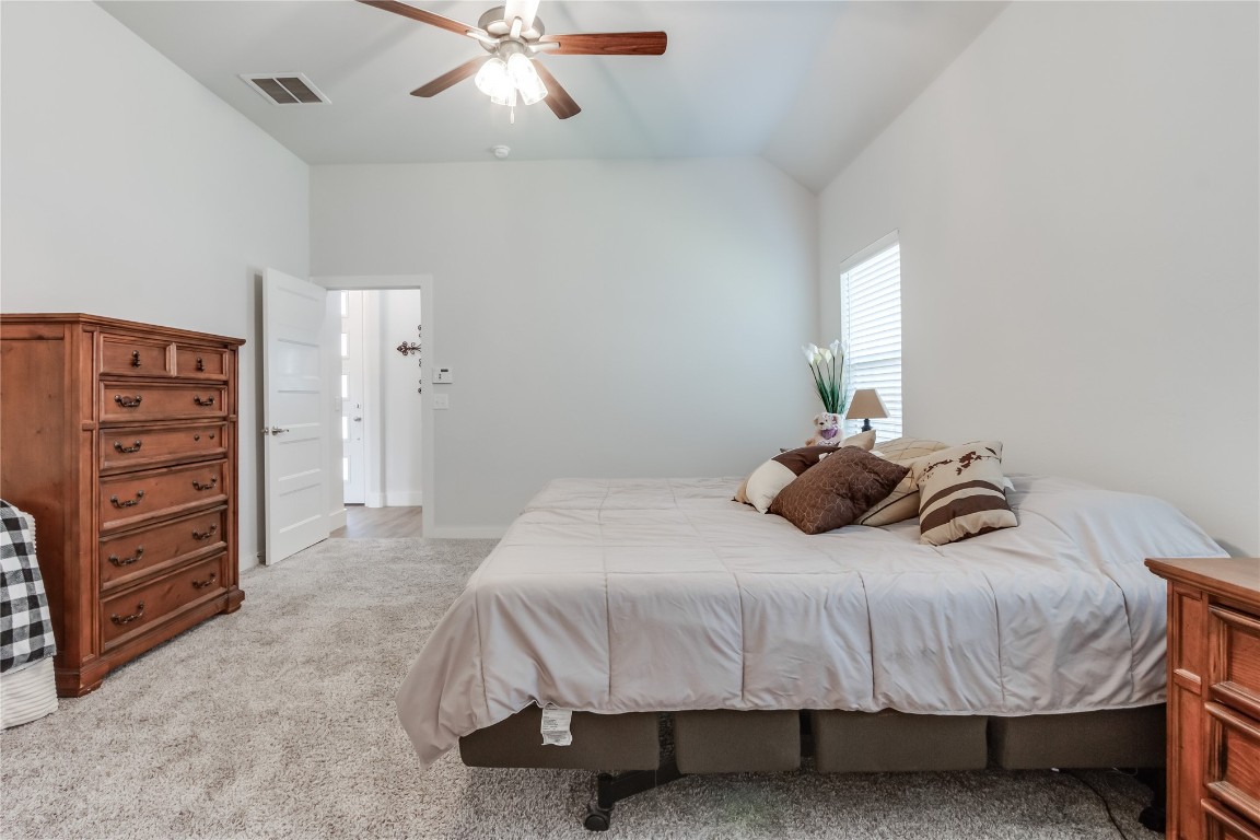 11636 NW 109th Street, Yukon, OK 73099 bedroom with vaulted ceiling, ceiling fan, and light carpet