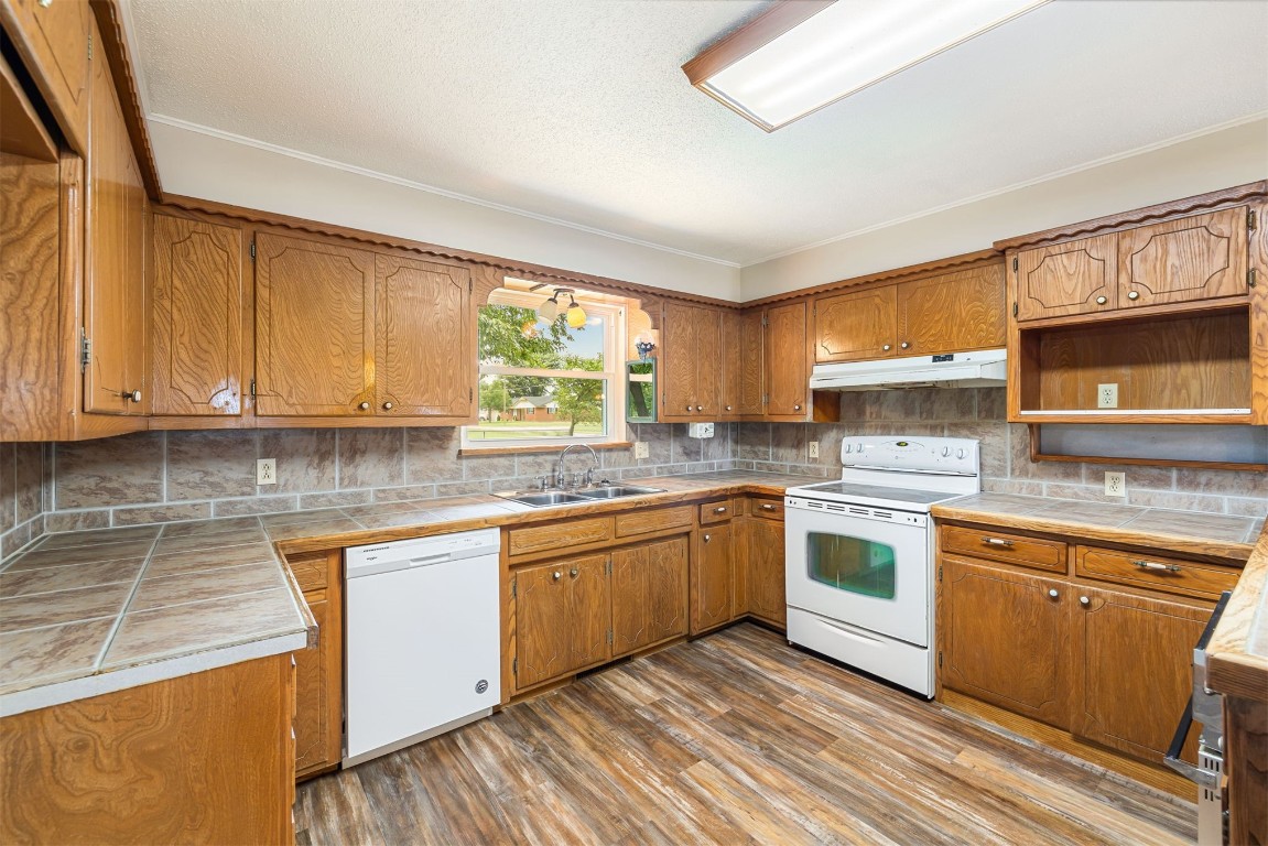 2500 S Choctaw Avenue, El Reno, OK 73036 kitchen with sink, white appliances, backsplash, tile countertops, and wood-type flooring
