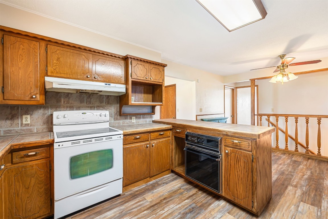 2500 S Choctaw Avenue, El Reno, OK 73036 kitchen with white electric stove, oven, hardwood / wood-style flooring, tasteful backsplash, and ceiling fan