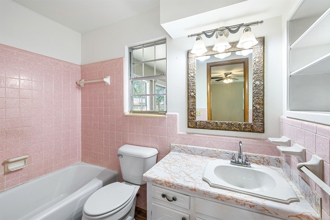 2500 S Choctaw Avenue, El Reno, OK 73036 full bathroom featuring tiled shower / bath, tile walls, backsplash, toilet, and vanity