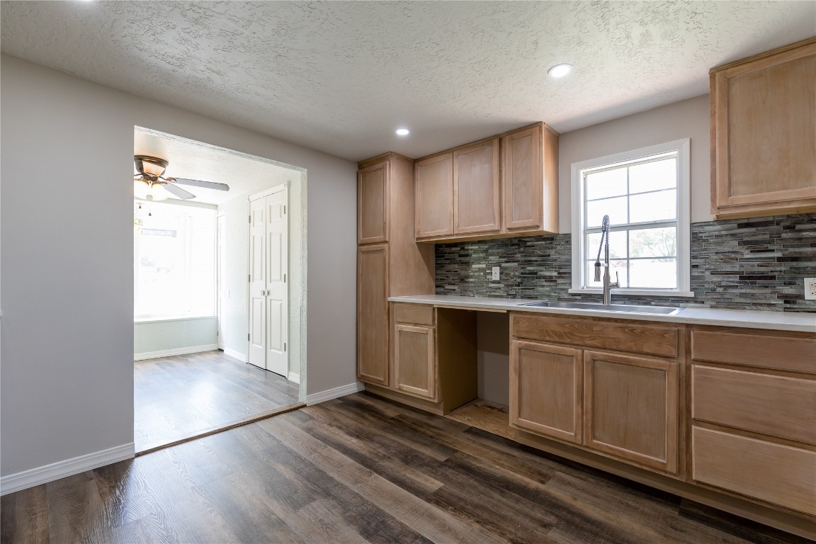 521 N State Avenue, Elk City, OK 73644 kitchen with ceiling fan, a textured ceiling, sink, backsplash, and dark hardwood / wood-style floors