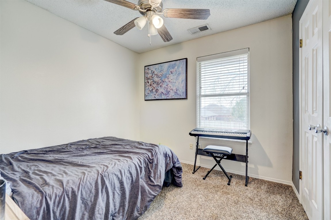 1325 Del Norte Drive, Edmond, OK 73003 bedroom featuring a textured ceiling, carpet floors, and ceiling fan