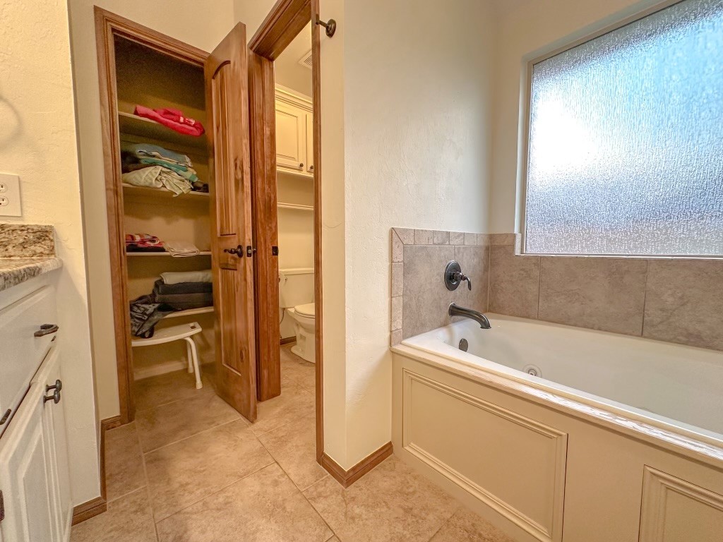 9116 NW 140th Street, Yukon, OK 73099 bathroom featuring tile floors, a bath to relax in, vanity, and toilet