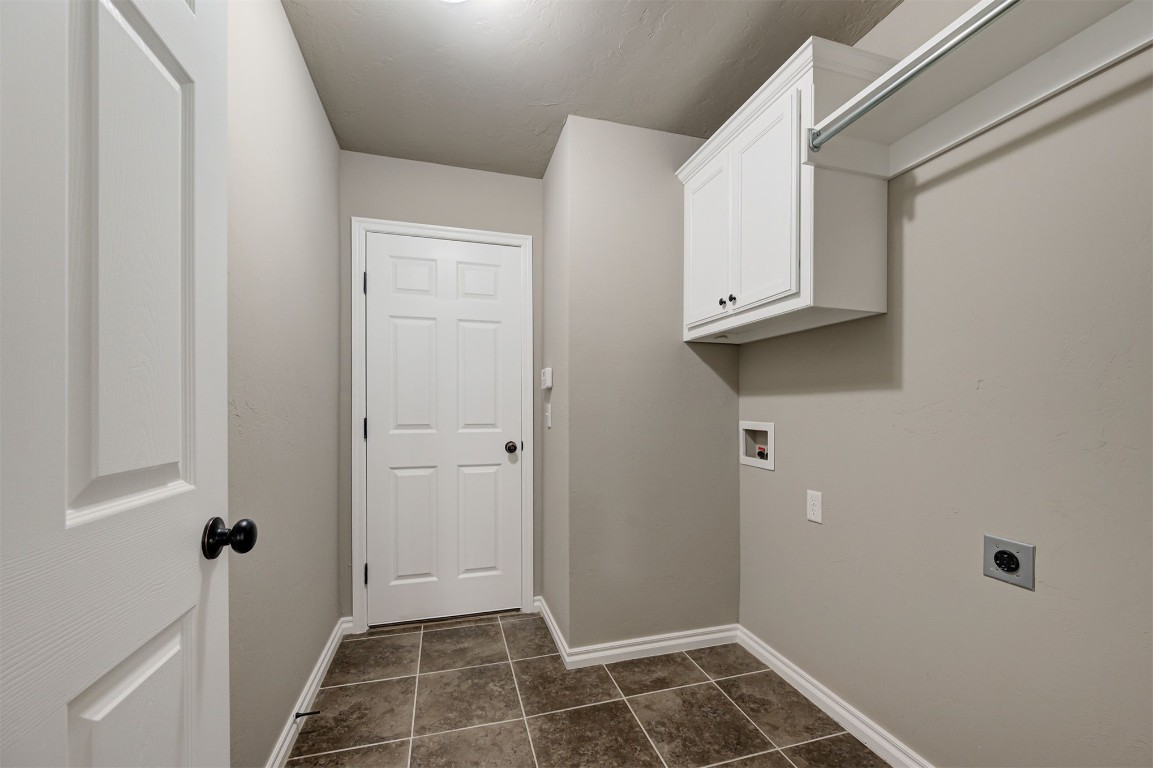 16304 Iron Ridge Road, Edmond, OK 73013 clothes washing area with electric dryer hookup, dark tile floors, cabinets, and washer hookup