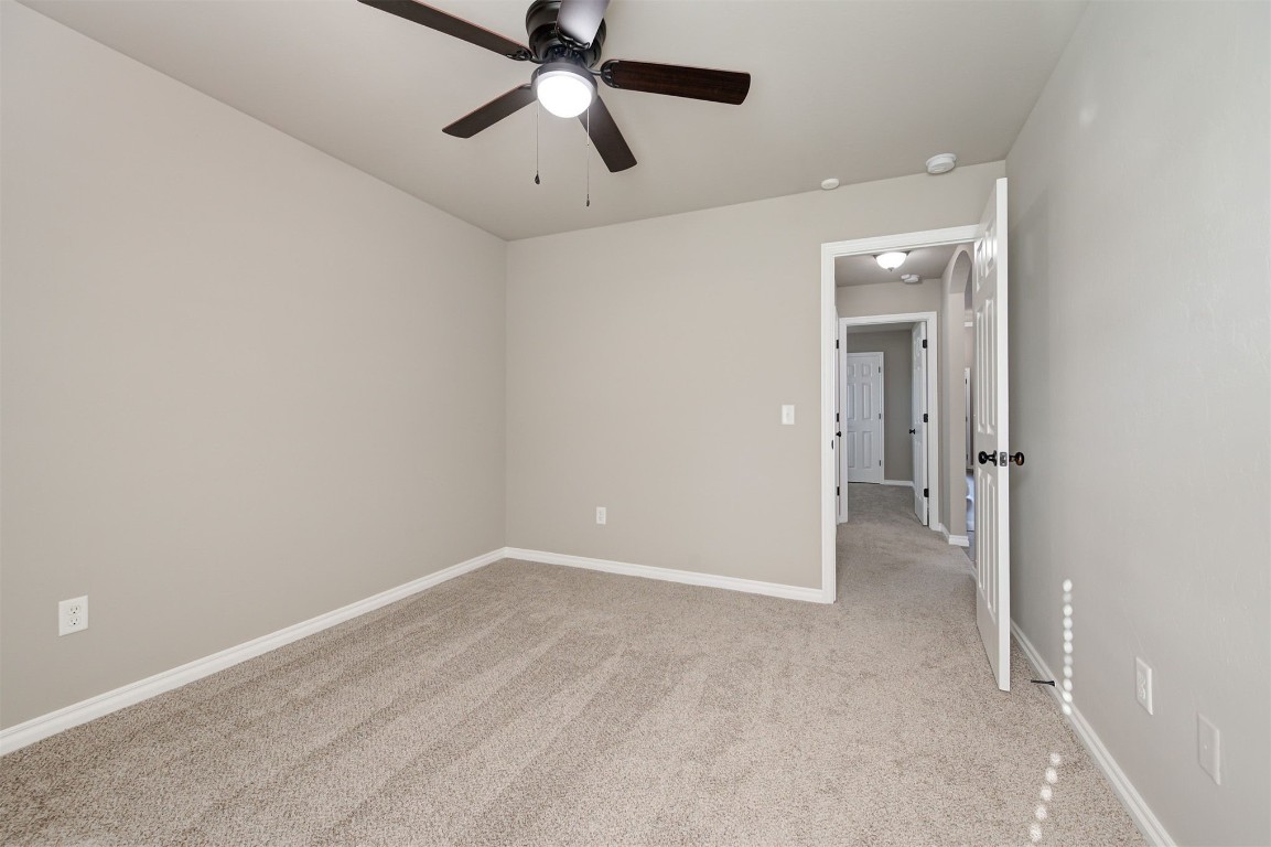 16304 Iron Ridge Road, Edmond, OK 73013 unfurnished room with light carpet and ceiling fan