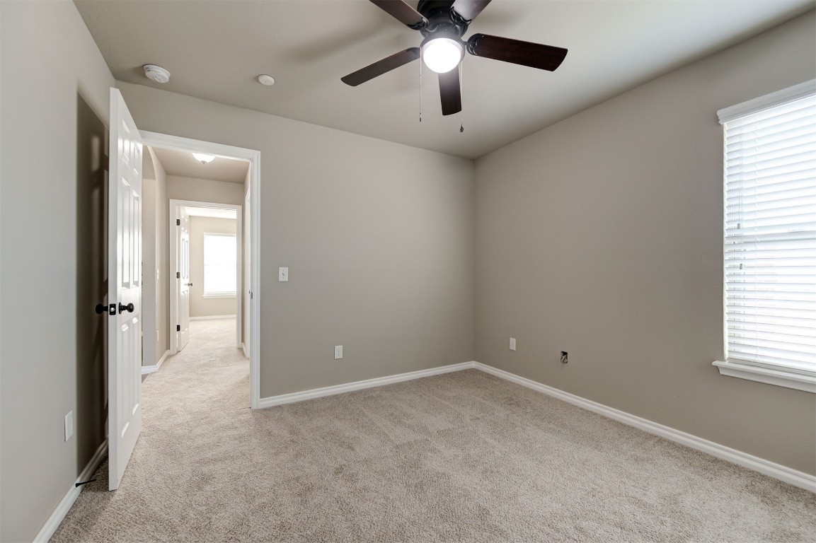 16304 Iron Ridge Road, Edmond, OK 73013 unfurnished room featuring light carpet, ceiling fan, and a wealth of natural light