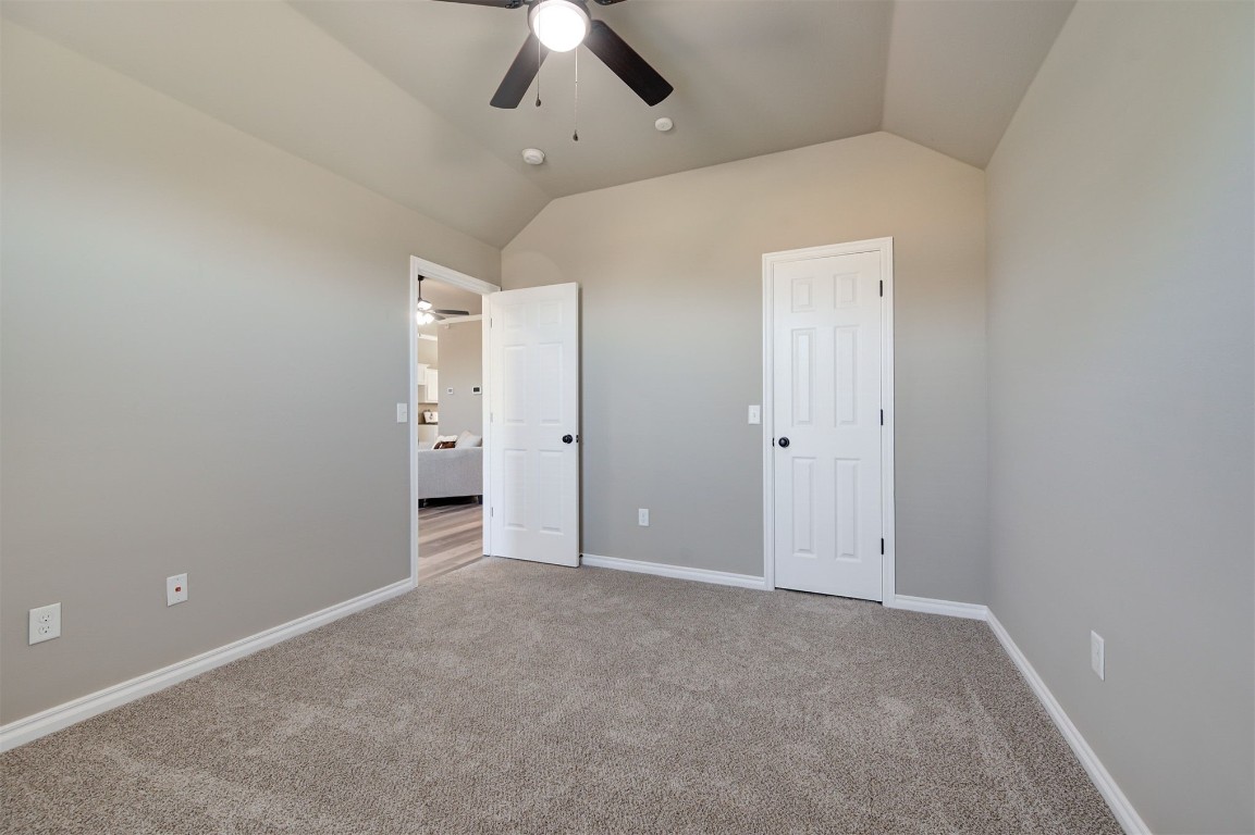 16304 Iron Ridge Road, Edmond, OK 73013 unfurnished bedroom featuring lofted ceiling, ceiling fan, and carpet
