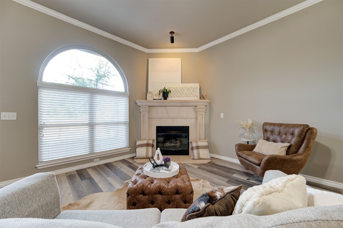 16304 Iron Ridge Road, Edmond, OK 73013 living room with hardwood / wood-style flooring, ornamental molding, and a fireplace