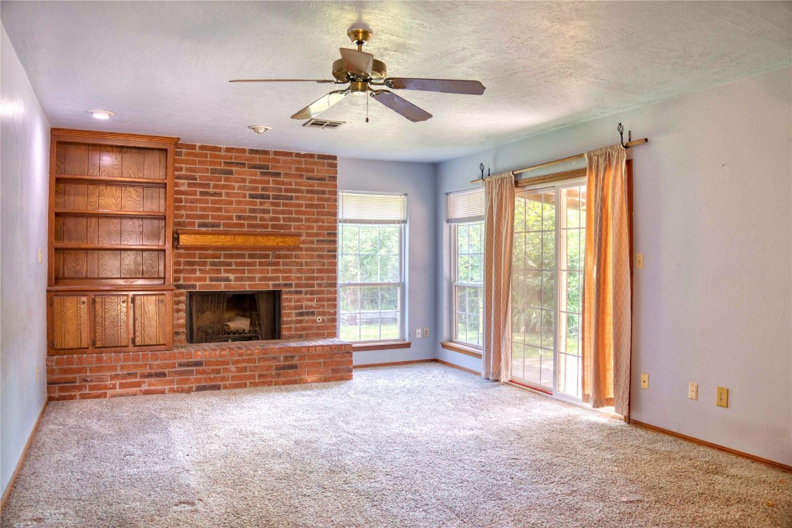 213 Falcon Court, Norman, OK 73069 unfurnished living room featuring ceiling fan, a brick fireplace, carpet flooring, and a textured ceiling