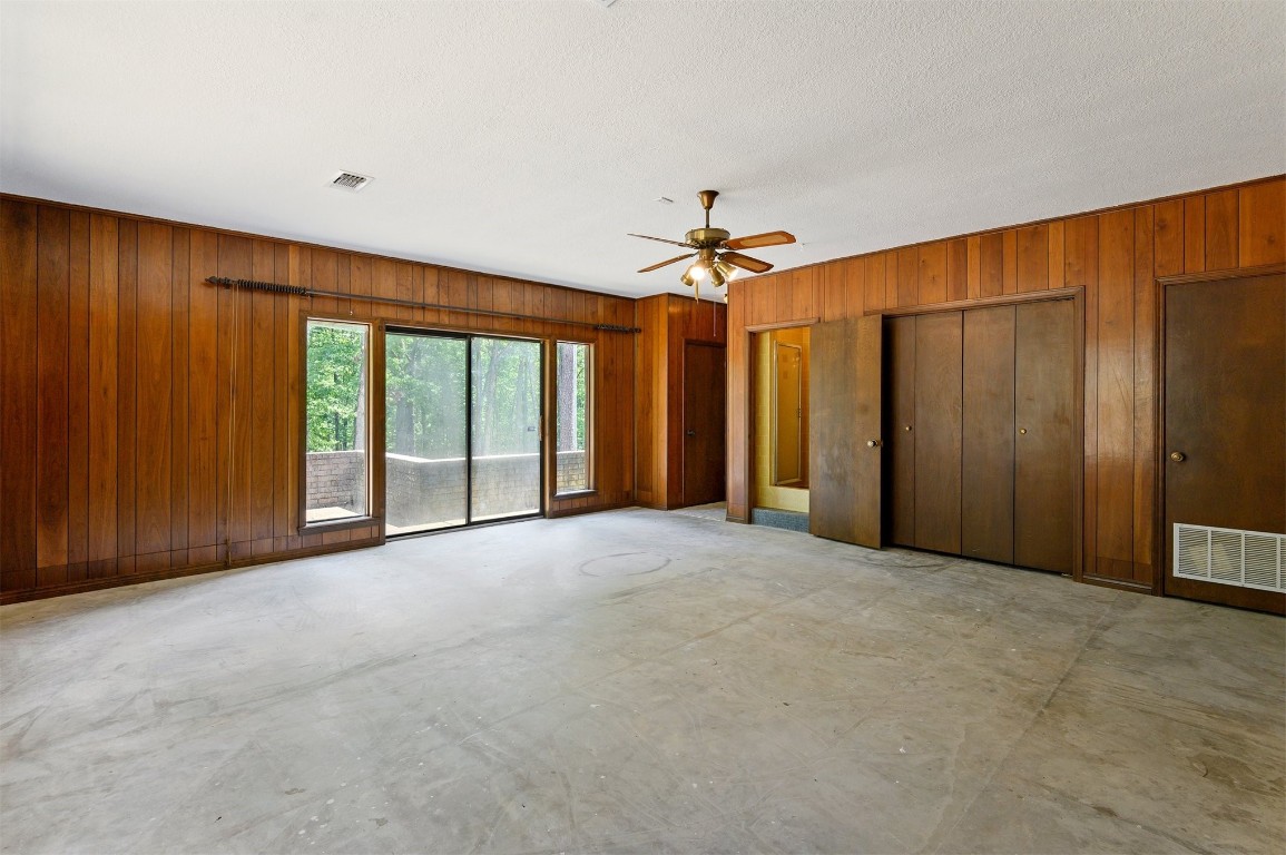688 Old Hochatown Road, Broken Bow, OK 74728 empty room with wooden walls, ceiling fan, and a textured ceiling