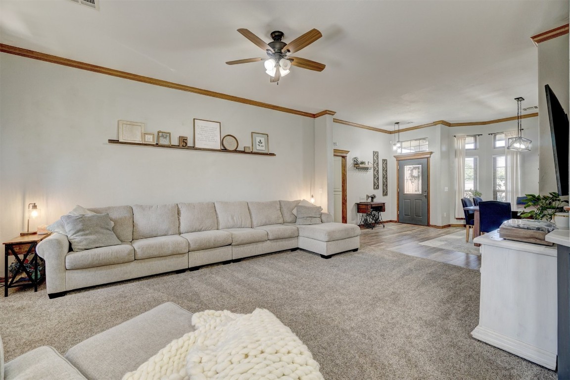 4005 Scissortail Drive, Yukon, OK 73099 carpeted living room featuring ornamental molding and ceiling fan
