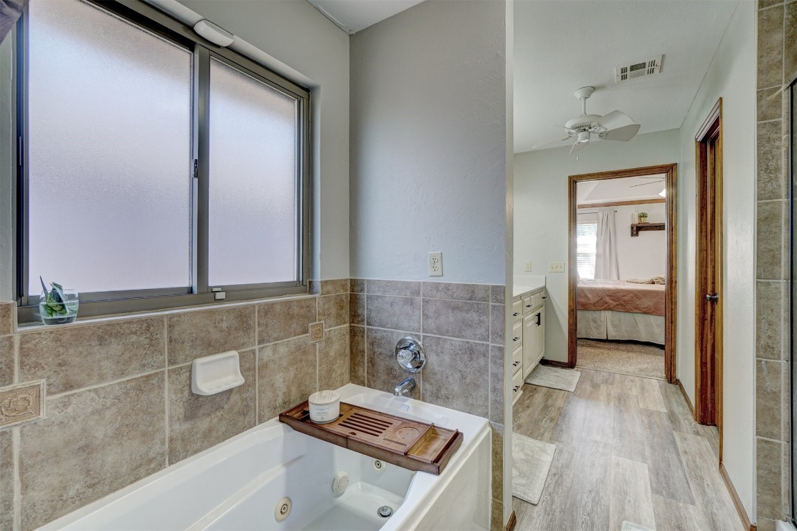 4005 Scissortail Drive, Yukon, OK 73099 bathroom with tile walls, wood-type flooring, ceiling fan, and vanity