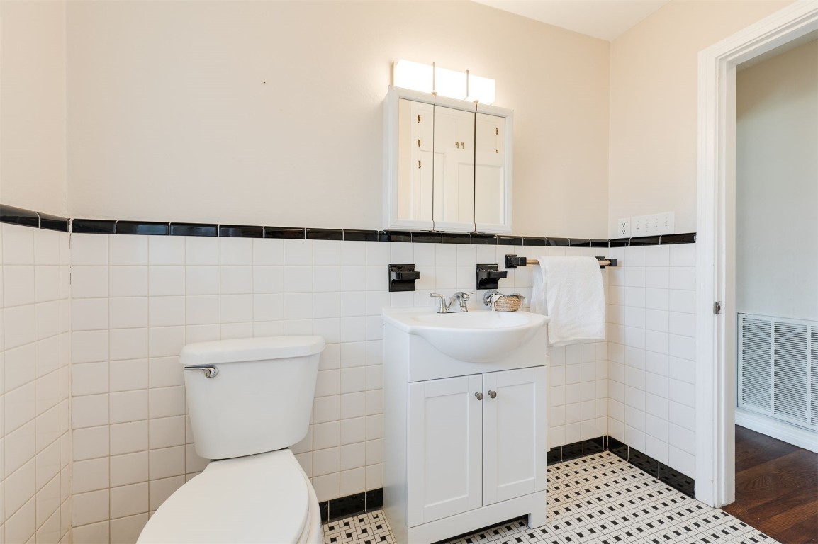 2707 NW 33 Street, Oklahoma City, OK 73112 bathroom featuring wood-type flooring, tile walls, vanity, and toilet