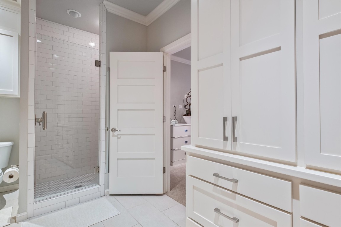 1200 Marlboro Lane, Nichols Hills, OK 73116 bathroom with ornamental molding, a shower with door, toilet, and tile floors