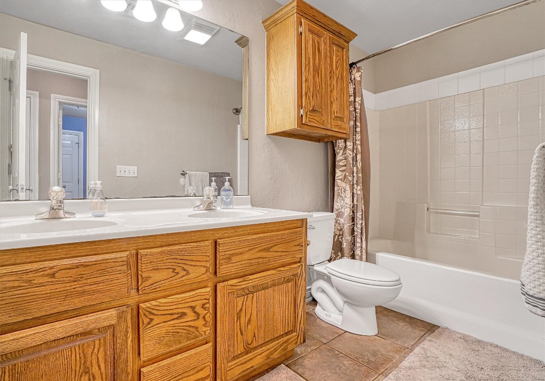 2910 Hunter Pointe, Altus, OK 73521 full bathroom featuring oversized vanity, shower / bath combo, toilet, tile floors, and dual sinks