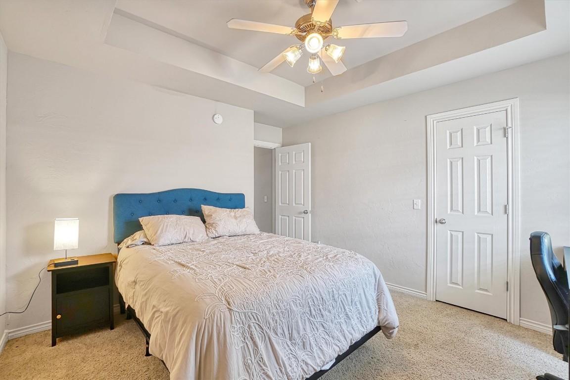 2910 Hunter Pointe, Altus, OK 73521 bedroom featuring light colored carpet, ceiling fan, and a raised ceiling