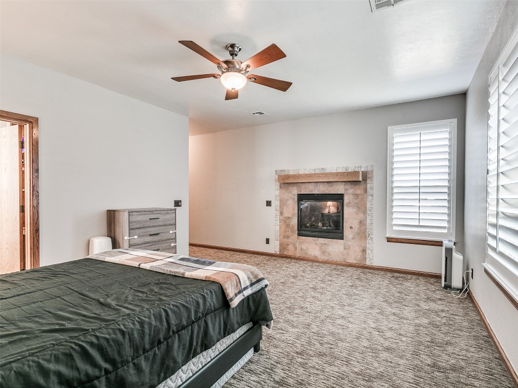 2900 Big Sky Circle, Yukon, OK 73099 carpeted bedroom with ceiling fan and a fireplace
