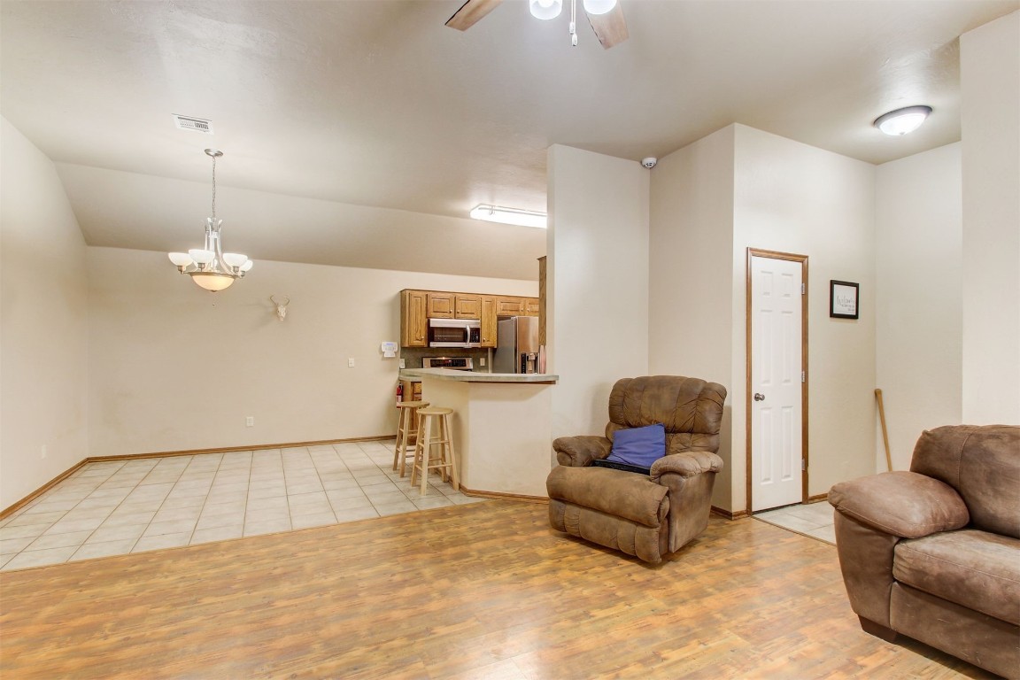 1306 SW 25th Street, Moore, OK 73170 living area featuring ceiling fan with notable chandelier, vaulted ceiling, and light tile floors