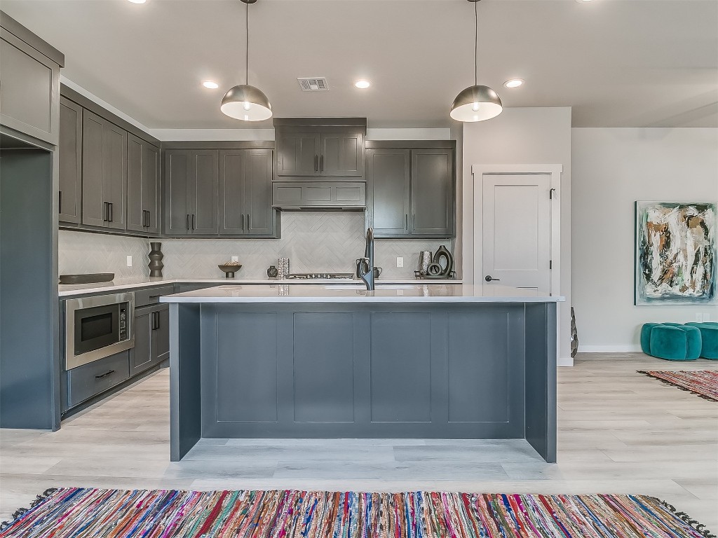 1735 NW 14th Street, #A&B, Oklahoma City, OK 73106 kitchen featuring tasteful backsplash, light hardwood / wood-style floors, and stainless steel microwave
