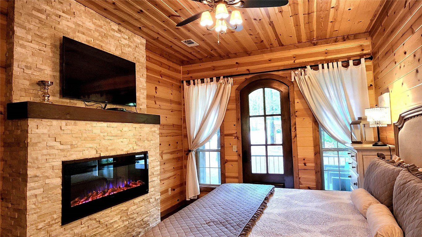 57 Mayflower Circle, Broken Bow, OK 74728 bedroom with wooden ceiling, wood walls, and a fireplace