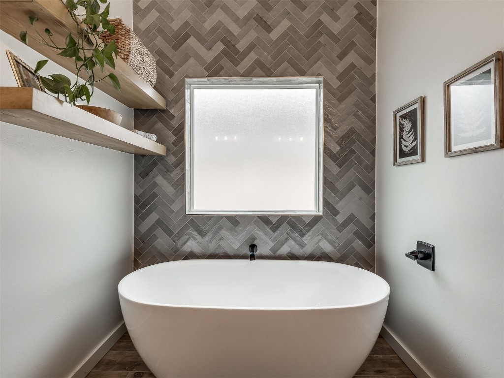 2300 El Cajon Street, Edmond, OK 73034 bathroom featuring tile walls, hardwood / wood-style flooring, and a bath to relax in