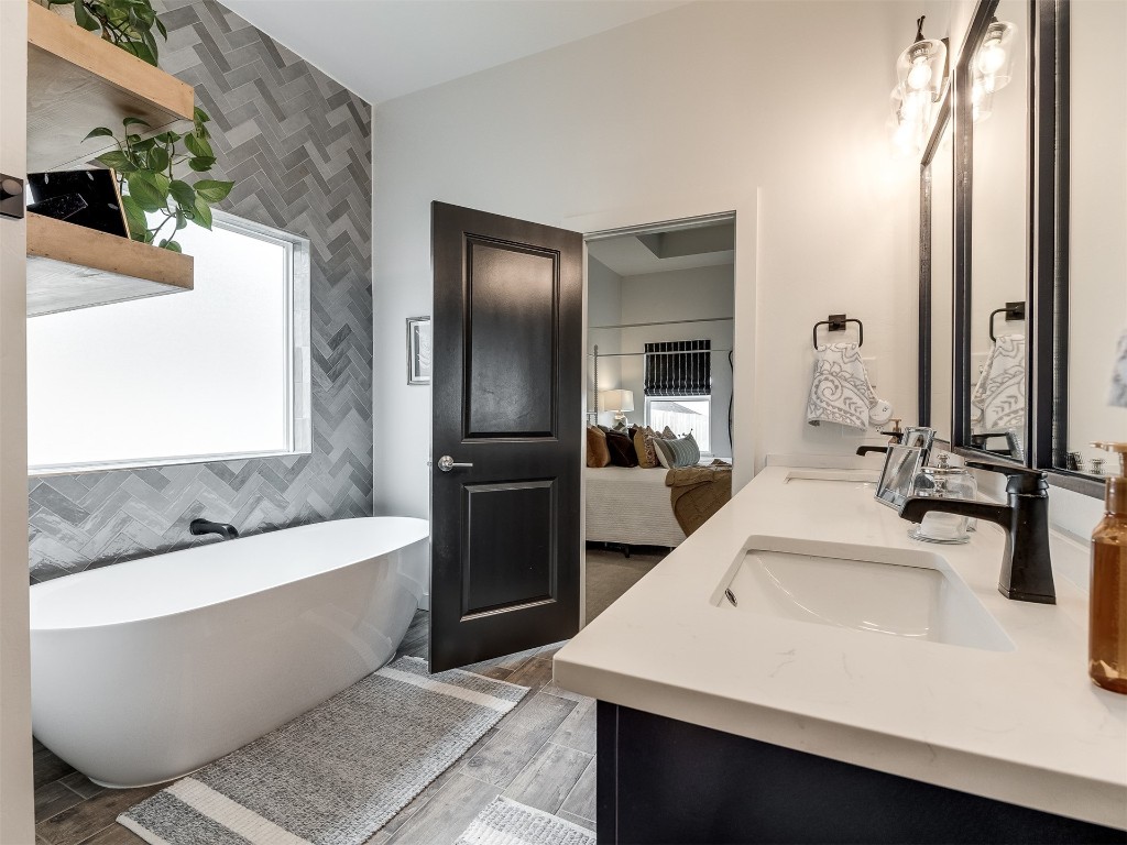 2300 El Cajon Street, Edmond, OK 73034 bathroom featuring double sink vanity, a healthy amount of sunlight, a bathtub, and tile walls