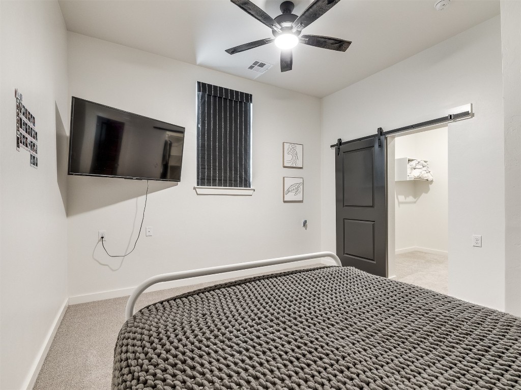2300 El Cajon Street, Edmond, OK 73034 bedroom featuring carpet flooring, ceiling fan, and a barn door