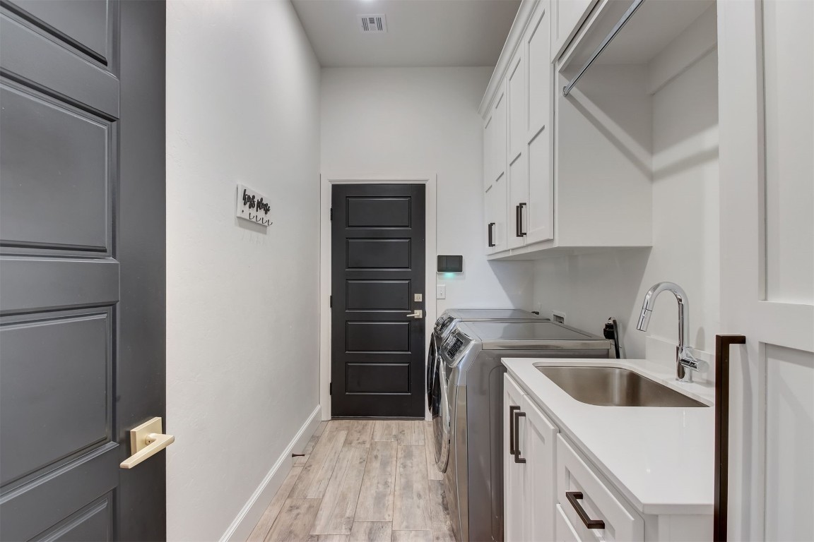 9224 NW 82nd Street, Yukon, OK 73099 washroom featuring washing machine and dryer, sink, light hardwood / wood-style floors, and cabinets