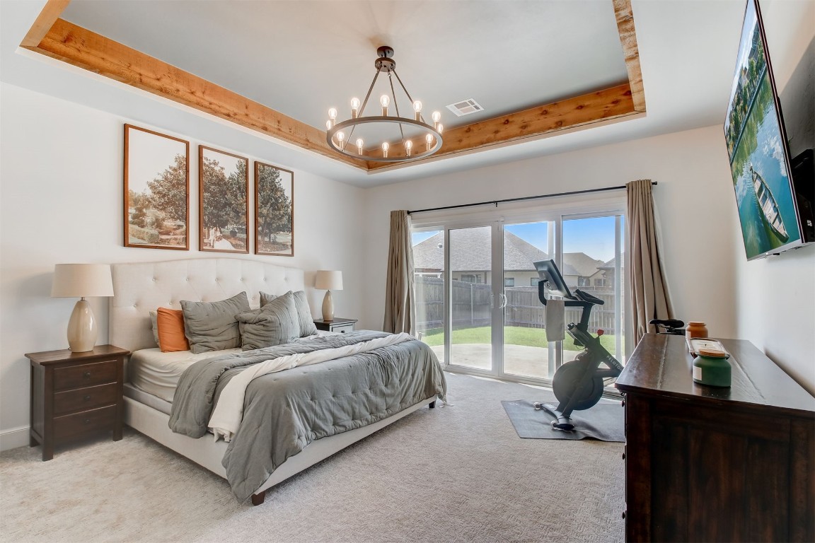 9224 NW 82nd Street, Yukon, OK 73099 carpeted bedroom featuring a raised ceiling, access to outside, and a chandelier