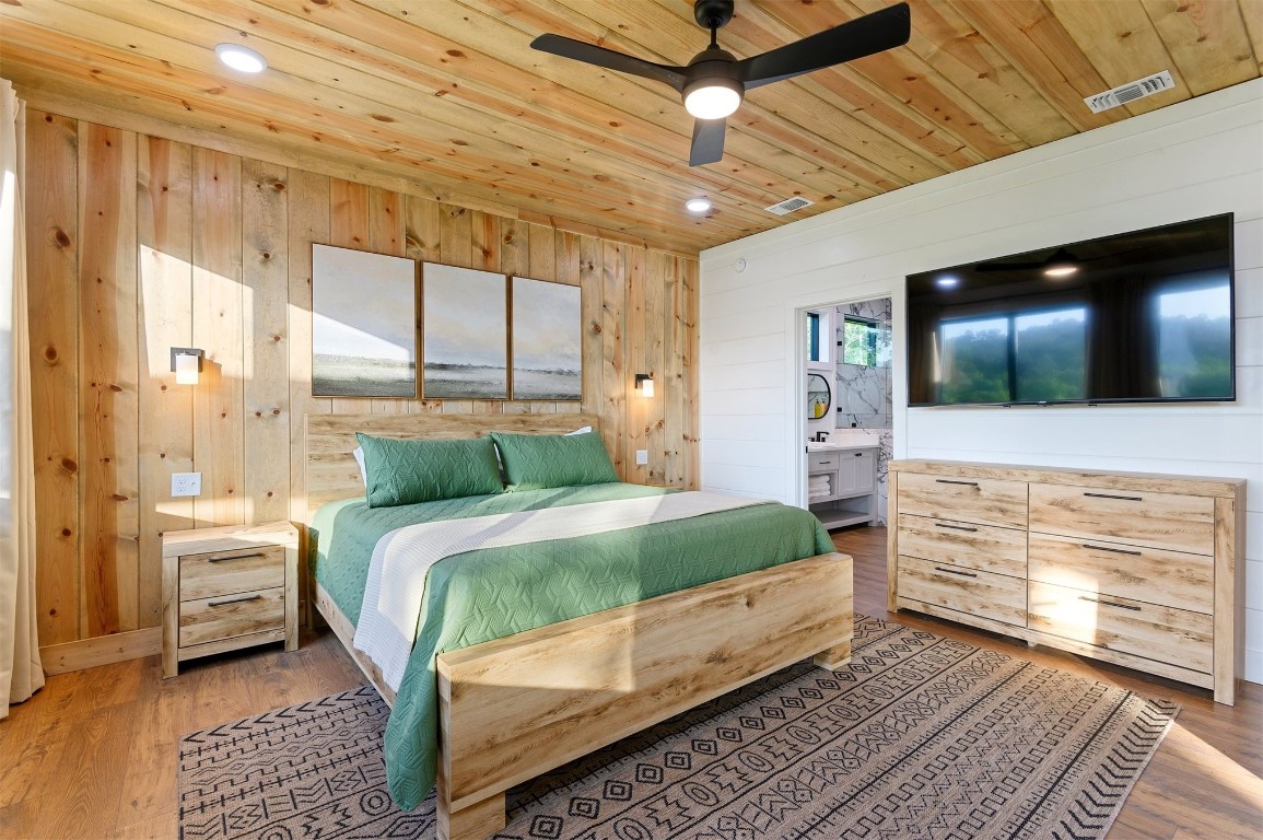 262 Forest Brook Loop, Broken Bow, OK 74728 bedroom featuring wood-type flooring, ensuite bath, wooden walls, and wood ceiling