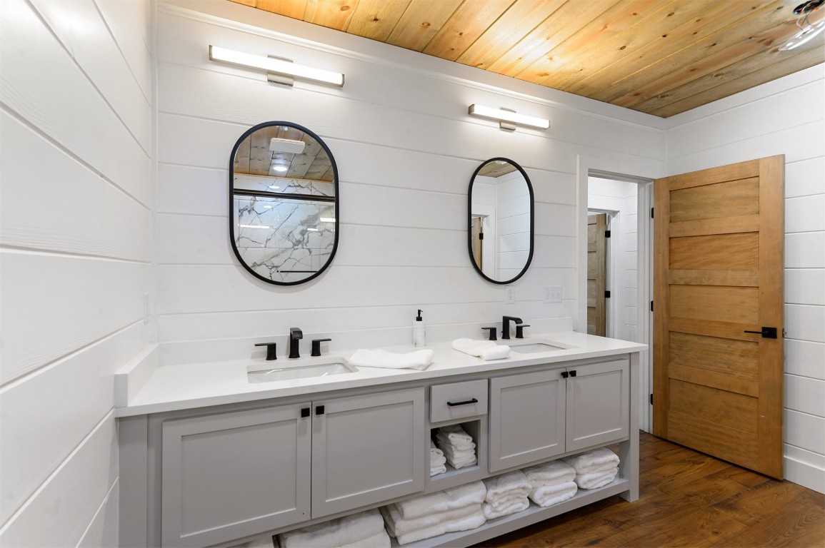 262 Forest Brook Loop, Broken Bow, OK 74728 bathroom featuring wood walls, wooden ceiling, double vanity, and hardwood / wood-style floors